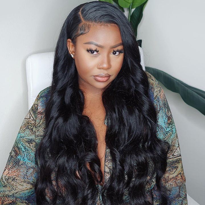 Woman with tattoos on her arm wearing a red top, modeling an Ishow Beauty body wave HD lace front wig made of 100% human hair in natural black.