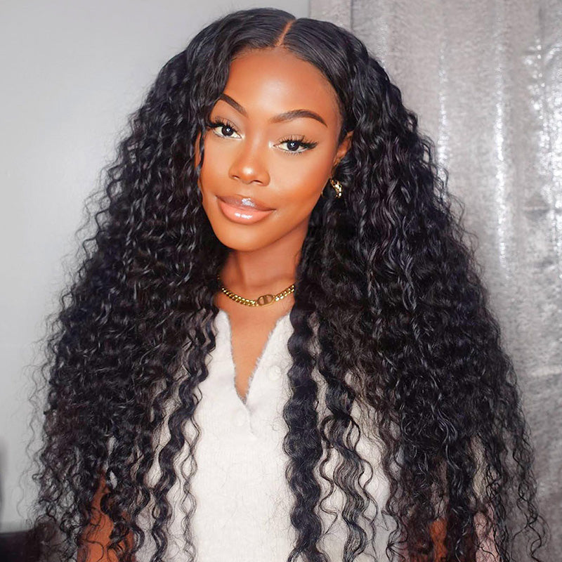 Woman wearing long natural black deep wave wig with a 13x4 frontal HD lace in an indoor setting, showcasing the deep wave texture and pre-plucked hairline.