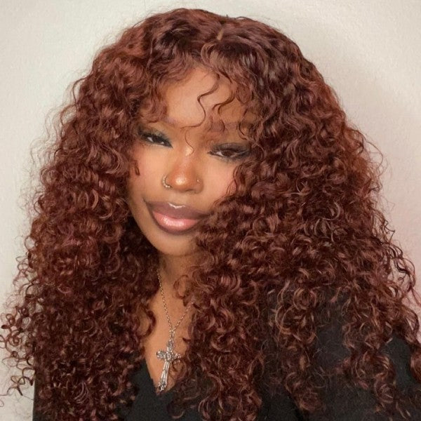 Woman with long, deep wave, reddish-brown 13x4 lace frontal wig wearing a white sleeveless top, posing indoors on a staircase
