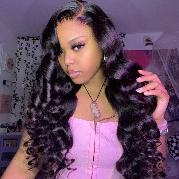 Woman wearing a Brazilian body wave human hair wig styled in long, natural black waves. The 30-inch wig has a 4x4 HD lace closure.