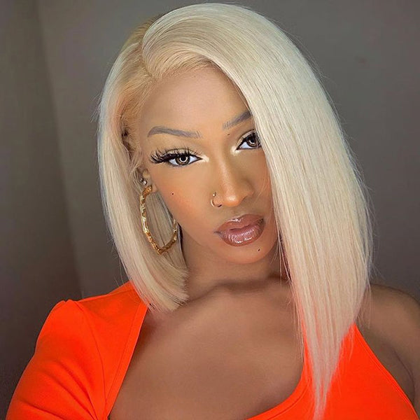 Woman with 613 honey blonde straight short bob wig and pre-plucked 13x4 lace frontal, wearing bright orange top, sitting in red vehicle interior.