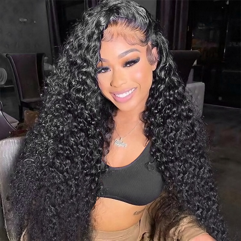 Woman with long deep wave lace frontal wig in natural black, showcasing voluminous curls in a modern kitchen setting. The wig is made from 100% human hair, offering a glamorous look.
