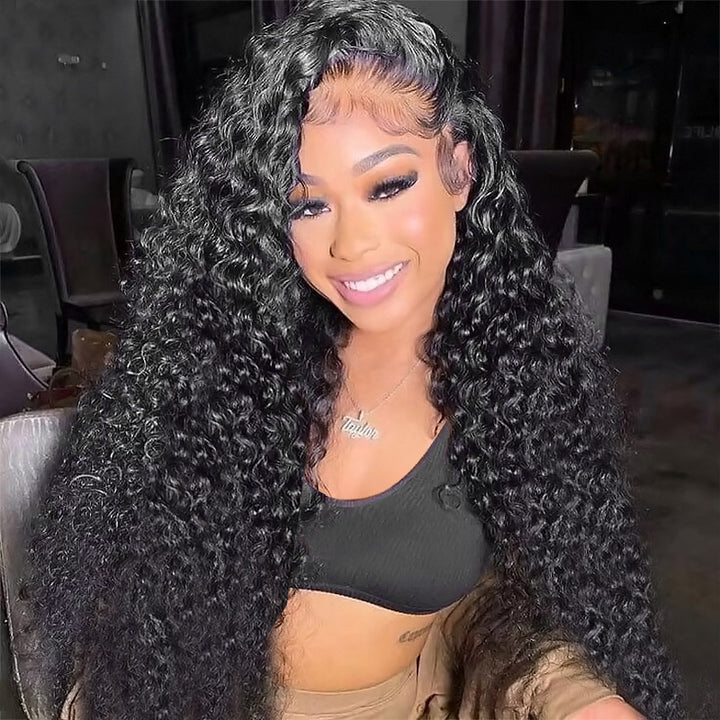 Woman with long deep wave lace frontal wig in natural black, showcasing voluminous curls in a modern kitchen setting. The wig is made from 100% human hair, offering a glamorous look.