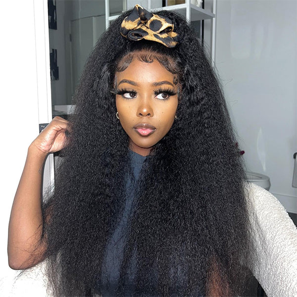Woman wearing a long kinky straight glueless wig with HD lace frontal from Ishow Beauty while posing indoors with framed pictures in the background.