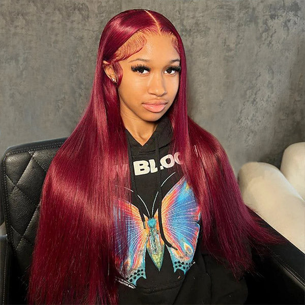 Woman showcasing Ishow Beauty long straight burgundy 99J HD lace wig with pre-plucked hairline, wearing a black hoodie with white text, and holding a bag with hair care products.
