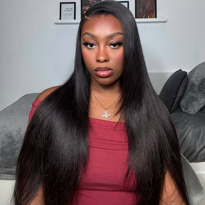 Woman with long black yaki straight hair wig wearing a red top in a casual indoor setting