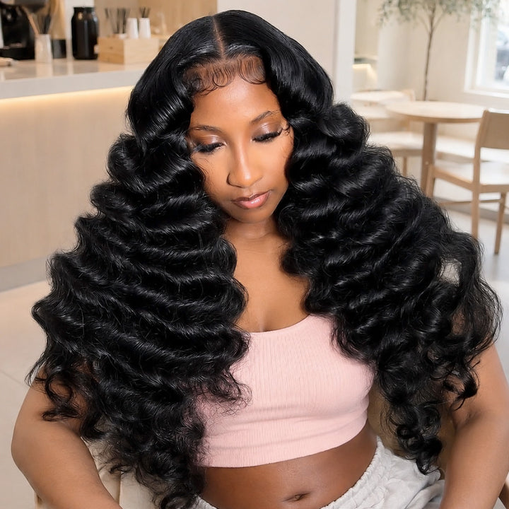 A Woman Wearing A Voluminous, Loose Deep Wave Wig With A Natural-Looking Part Line, Styled In A Bright, Modern Indoor Setting.