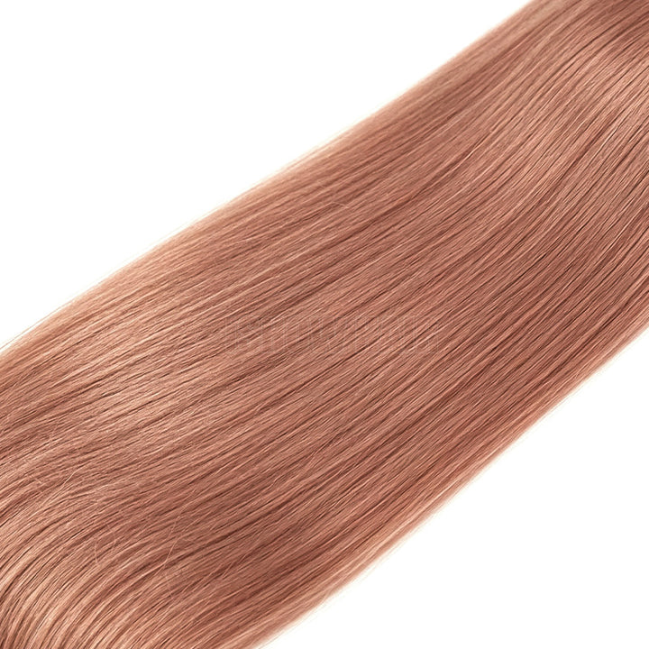 A Close-Up Of Straight, Silky Human Hair Extensions, Shown Diagonally Against A Solid White Background.