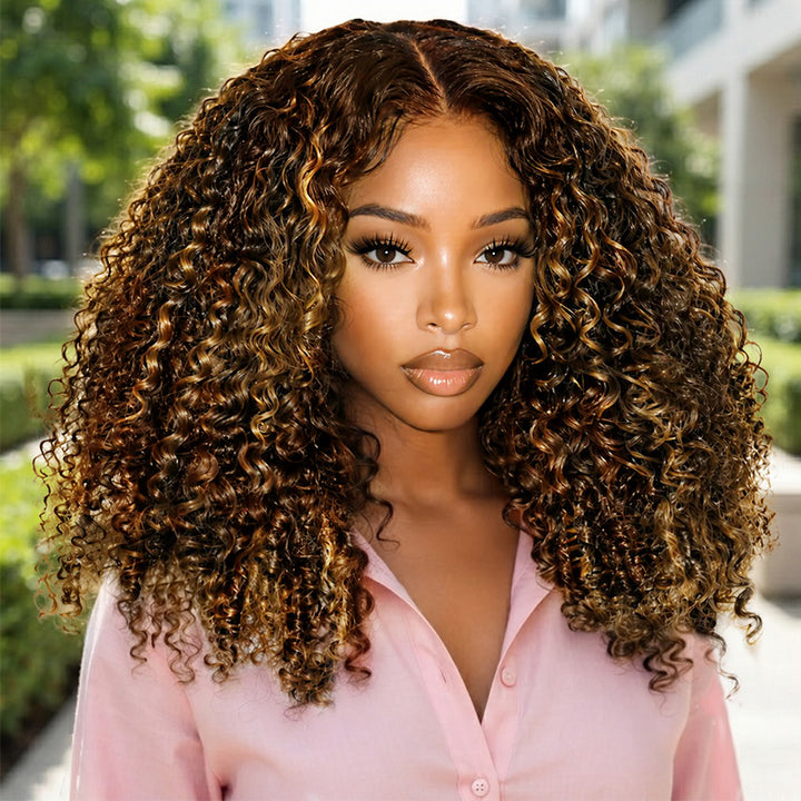 A Woman Wearing A Full, Voluminous P4/27 Hair. She Is Wearing A Light Pink Button-Up Shirt, With A Blurred Outdoor Garden Background.
