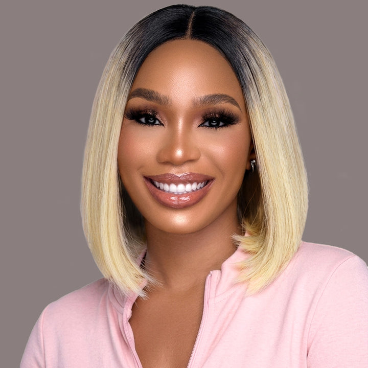 Woman With A T1B 613 Color Bob Wig Wearing A Pink Top Against A Gray Background